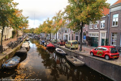 Fall colours along a canal with car, boat and bicycle parking in Haarlem