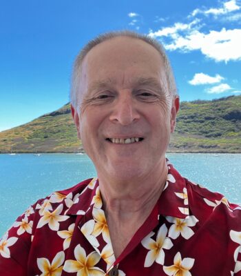Joe wearing his new Aloha shirt featuring Frangipangi flowers on a dark red background.